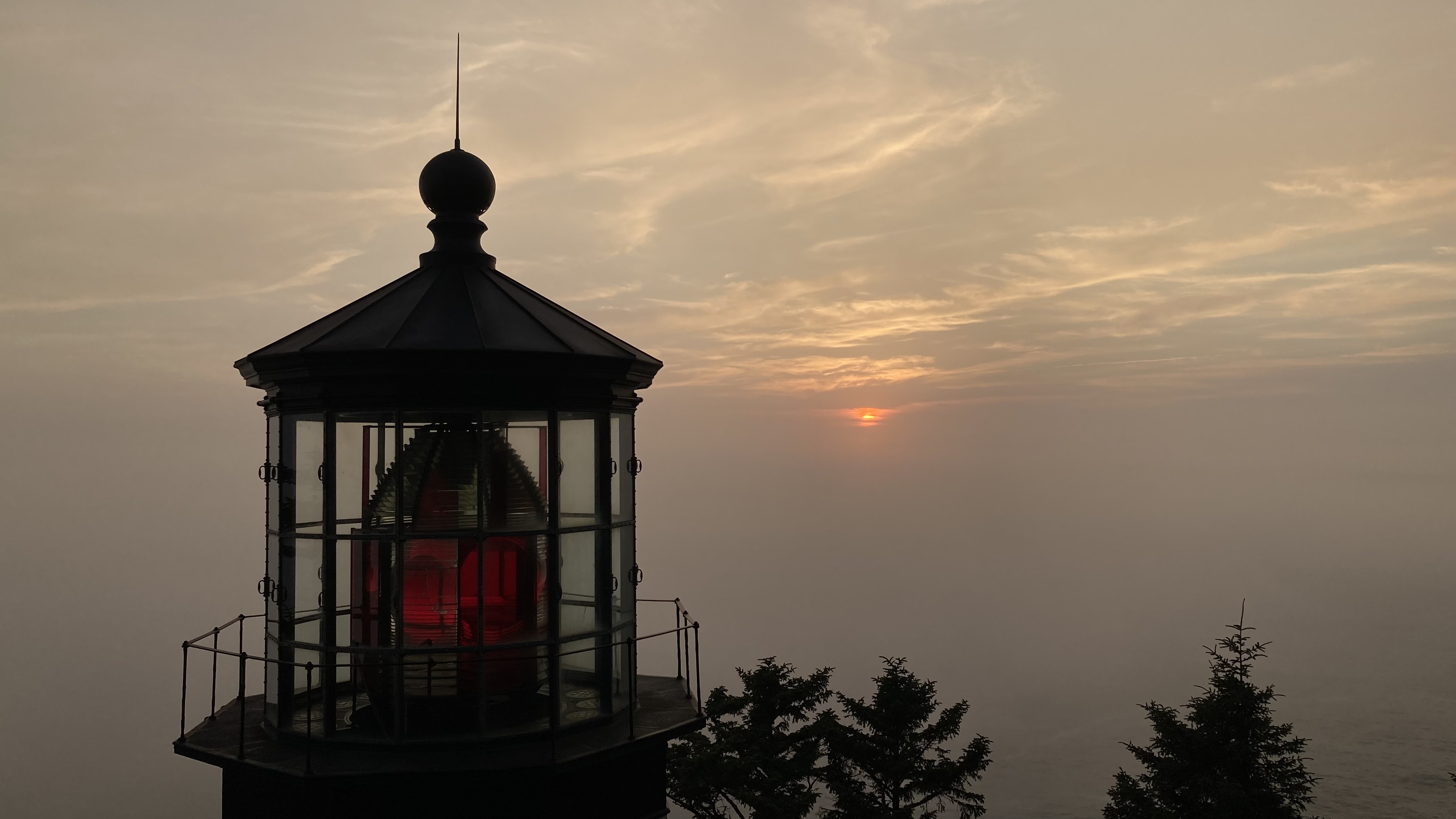 A lighthouse off the Oregon coast at sunset. The lighthouse is off; it's a historic site, not an active lighthouse. The sun casts its delicious orange glow through the red and white glass of the lighthouse. The beauty could make one weep, and has etched itself in my soul. I will never forget this sunset.